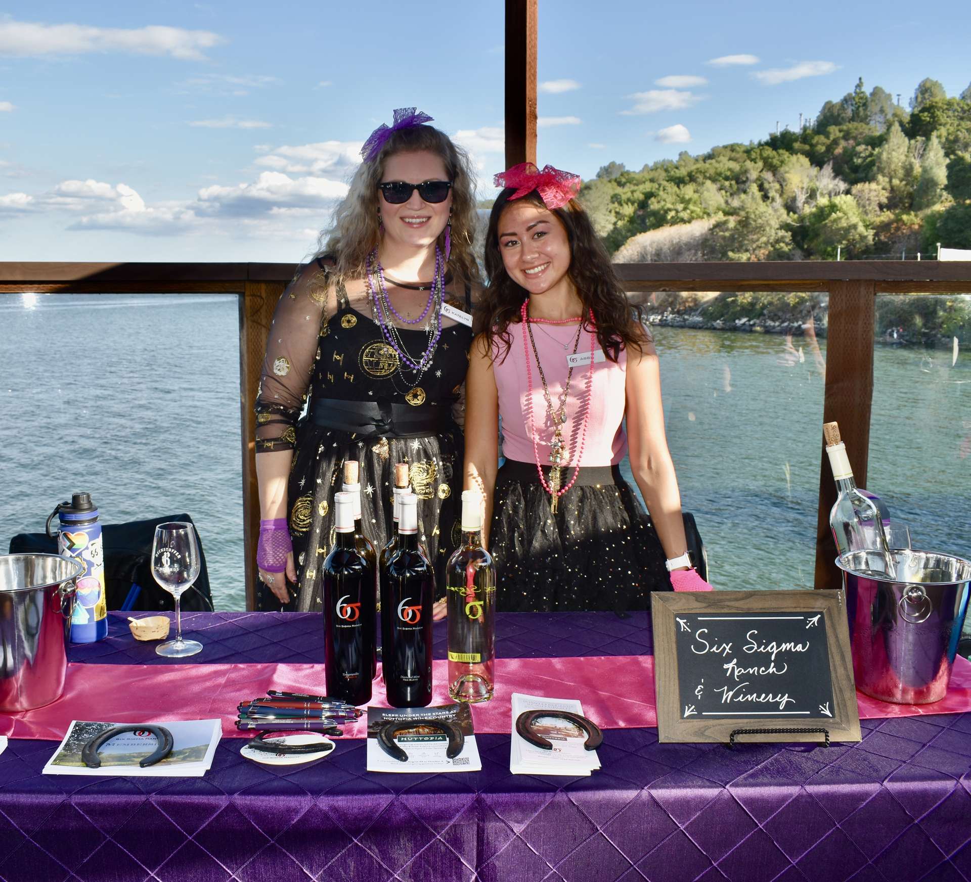 Two women at wine auction with lake backdrop